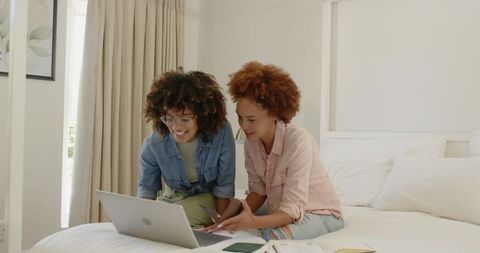 African American Women Collaborating on Laptop in Minimalist Bedroom Planning Finances