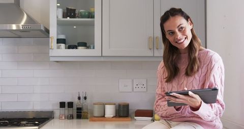Smiling woman in modern kitchen using tablet