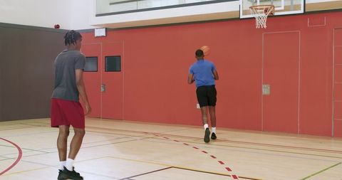 African american players practicing rotational shooting drill on indoor basketball court