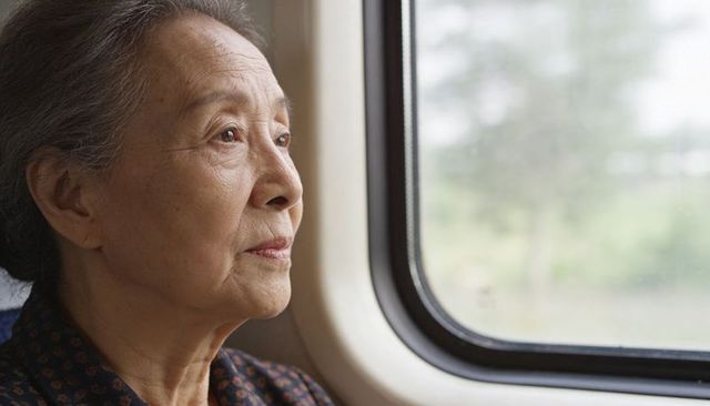 Senior asian woman gazing from train window, reflective elderly travel portrait