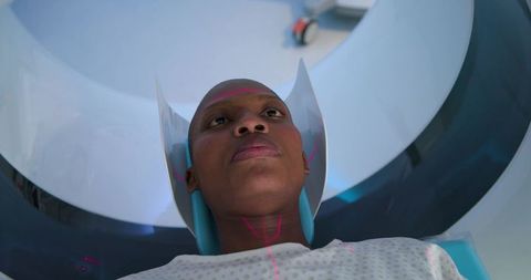 Female patient undergoing mri scan with head coil and laser alignment in clinical radiology
