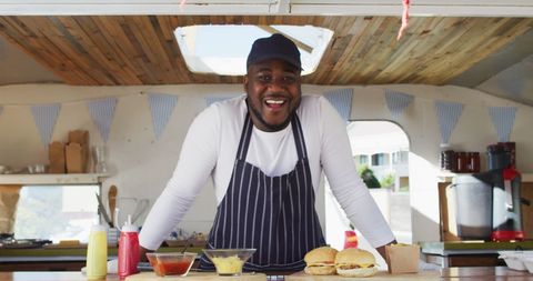 Smiling African American Man in Food Truck Serving Burgers