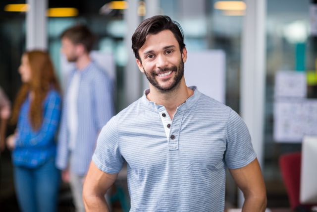 Image shows a confident male executive smiling in a modern office environment. Perfect for use in corporate websites, business presentations, HR recruitment materials, and articles related to office culture and professional life.