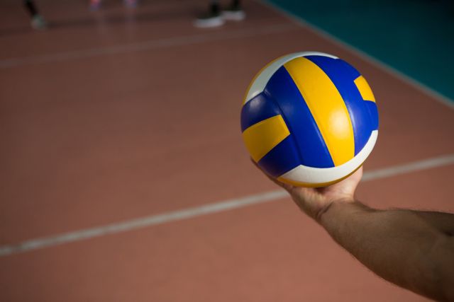 Cropped hand of sportsperson with volleyball at court