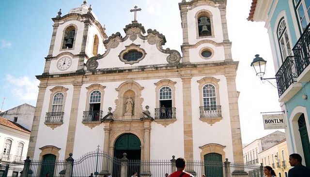 Baroque church facade with twin bell towers, clock, ornate niche and wrought-iron fence