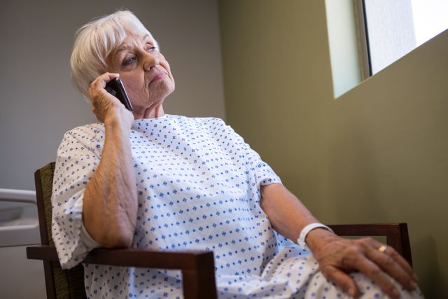 Senior patient talking on mobile phone in hospital