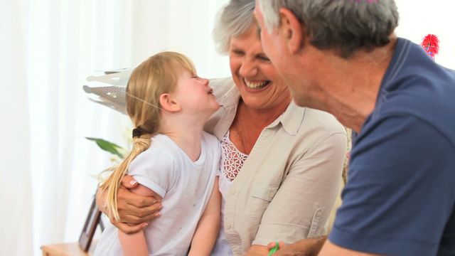 Scene captures joyful moments between elderly couple and granddaughter while celebrating a birthday at home. Ideal for illustrating familial love, generational connections, happiness, and the warmth of family gatherings. Suited for use in advertisements, family-oriented campaigns, or celebratory contexts.