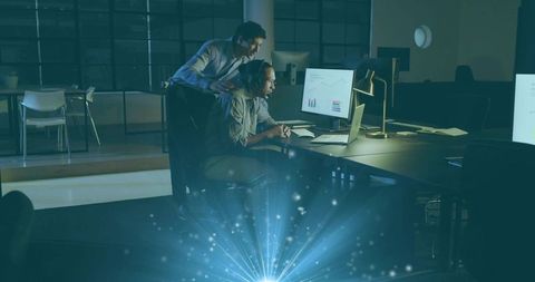 After-Hours Team Reviewing Data on Laptop and Monitor for Collaboration and Mentoring