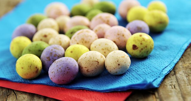 Close-up of colorful speckled mini eggs placed on vibrant napkins. Perfect for illustrating Easter celebrations, holiday decorations, candy displays, festive treats, and springtime themes.