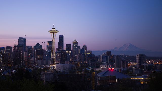 Seattle skyline featuring Space Needle at dusk with Mount Rainier in the background. Ideal for travel brochures, city guides, and promotional material highlighting Seattle's iconic scenery and tourist attractions.