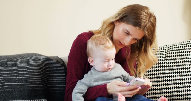 Mother Holding Baby While Using Smartphone on Couch - Download Free Stock Images Pikwizard.com