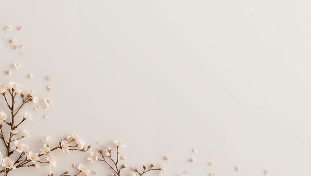 Delicate pale pink cherry blossom branches on cream background with scattered petals