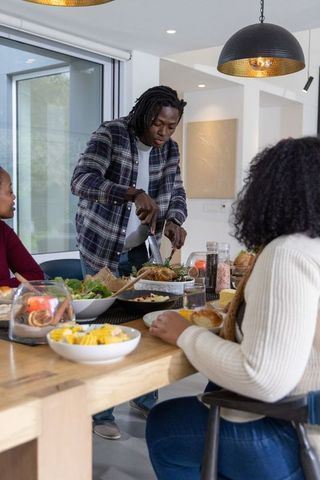 African american family sharing warm dinner man carving roasted turkey at dining table