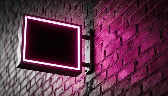 Magenta neon frame casting glow on urban brick wall with mounting bracket