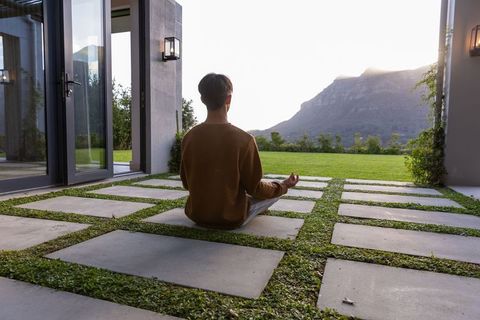 Person meditating on modern patio with concrete pavers and mountain view at sunrise