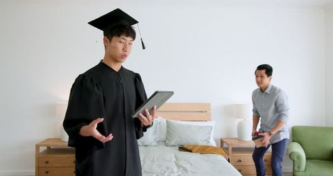 Father Congratulating Son on Graduation in Bedroom Setting