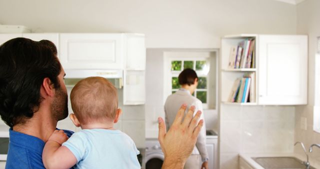 Father holding his baby and saying bye to his wife at home