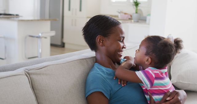 Happy african american mother and daughter sitting on sofa and hugging - Download Free Stock Photos Pikwizard.com
