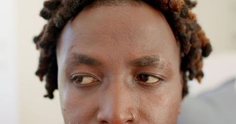 Closeup portrait of african man with twisted locks and hoop nose ring, contemplative gaze