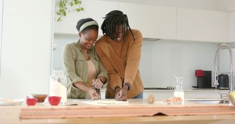 African American Couple Kneading Dough at Bright Modern Kitchen Island for Home Baking