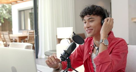Smiling Podcaster Talking into Microphone at Home Desk