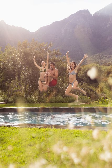 Group of friends enjoying a sunny day by jumping into a swimming pool in a backyard with a mountain view. Perfect for advertisements related to summer activities, outdoor fun, travel, and leisure. Ideal for use in social media posts, travel blogs, and lifestyle magazines.