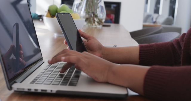 Close-up of person multitasking on laptop and smartphone - Download Free Stock Images Pikwizard.com