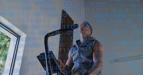 Man training on stationary bike in home gym with binary overlay digital fitness cardio workout