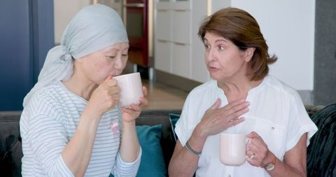 Diverse elderly women bonding over coffee on sofa