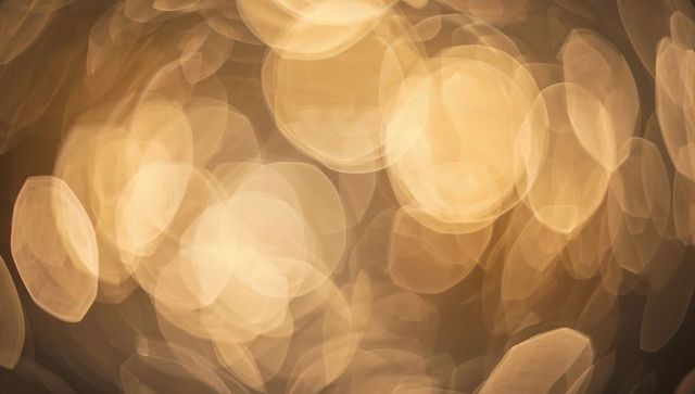 Golden bokeh orbs creating soft warm glow abstract background for holiday design