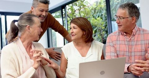 Happy Friends Collaborating Around Laptop in Bright Living Room