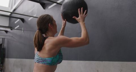 Athletic Woman Throws Medicine Ball Against Wall at Gym