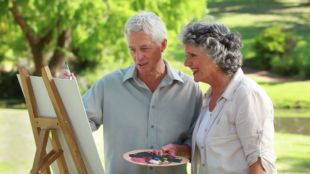 Older couple enjoying an outdoor painting session, fostering creativity and spending quality time in nature. Ideal for retirement community promotions, senior lifestyle blogs, and art-related content emphasizing leisure and hobbies.