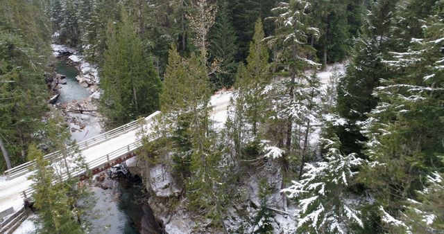 Aerial of bridge passing over the river in snow covered forest 4k