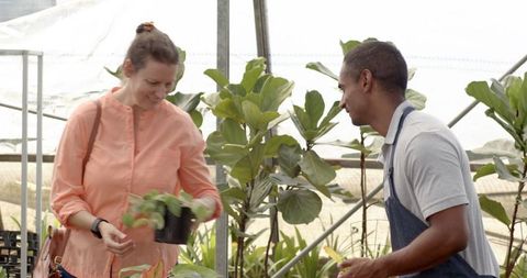 Customer and nursery attendant enjoying plants in greenhouse