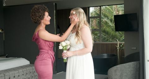 Bride and Bridesmaid Enjoying Pre-Wedding Moment in Modern Bedroom