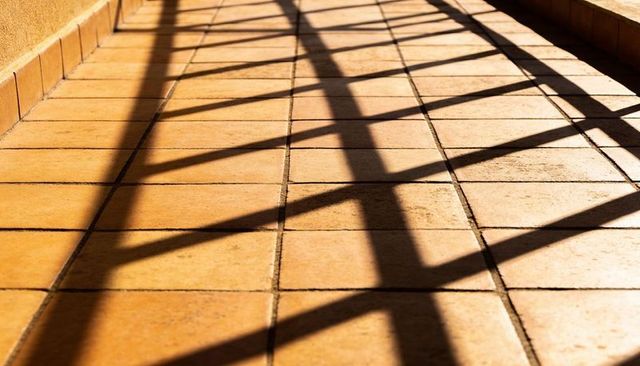 Sunlight casting lattice shadows across terracotta tiles on outdoor terrace