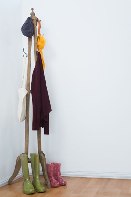 Hat, umbrella, jumper, grocery bags and wellington boots arranged on wooden stand