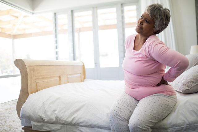 Senior woman having back pain in bedroom - Download Free Stock Photos Pikwizard.com