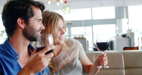 Joyful Couple Toasting with Red Wine in Sunny Restaurant