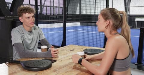 Young athletes enjoying coffee break at padel court table