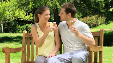 Happy Couple Enjoying Ice Cream Together in Sunny Park