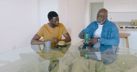 Father and Son Enjoying Casual Conversation at Glass-Top Table