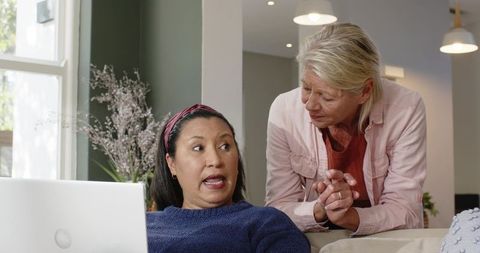 Diverse senior women collaborating on laptop at home