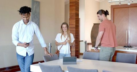 Friends Laughing Around Tablet at Casual Home Gathering