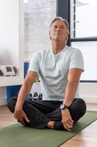 Senior man practicing seated yoga and breathwork at home for calm focused wellbeing
