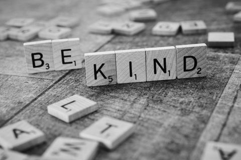 Scrabble tiles spelling 'be kind' in black and white