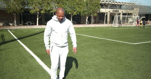 Man Observing Soccer Game on Sunny Day