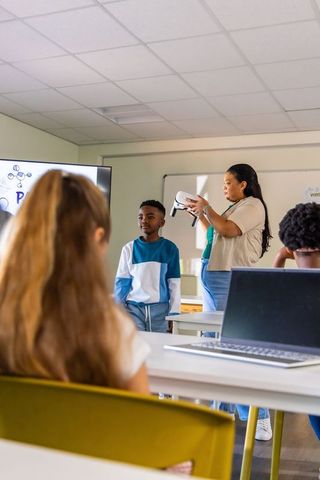 African american teacher demonstrating vr headset to students during tech lesson