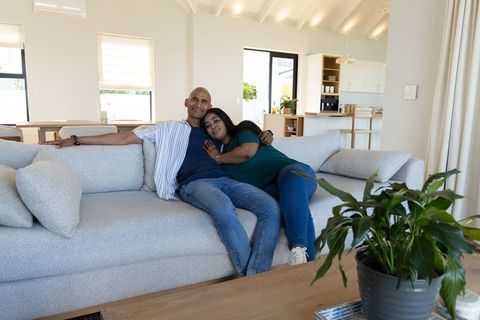 Middle-aged couple relaxing on light-gray sofa in bright modern minimalist living room